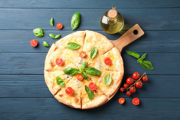 Pizza au fromage, tomates et huile d'olive sur fond de bois