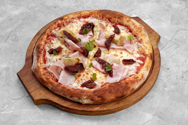 Pizza au jambon de veau fromage et tomates séchées sur une table grise