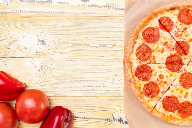 Pizza au pepperoni chaud sur une table rustique avec une fourchette et un couteau de table, vue de dessus