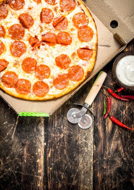 Pizza au pepperoni dans une boîte avec un couteau.