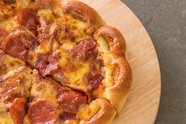 Pizza au pepperoni fait maison sur une plaque de bois