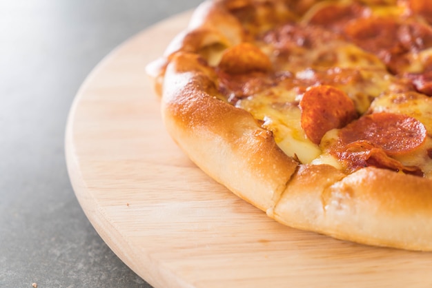 Pizza au pepperoni fait maison sur une plaque de bois