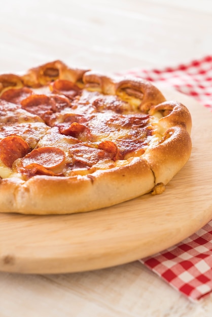 Pizza au pepperoni fait maison sur une plaque de bois