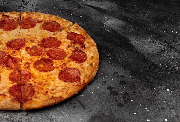 Pizza au pepperoni sur fond de béton noir. Vue de dessus avec espace copie.