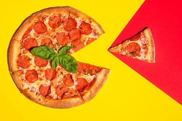 Pizza au pepperoni sur fond jaune-rouge coloré au basilic