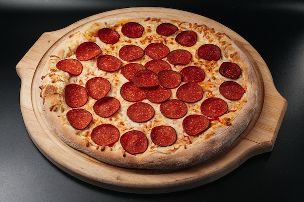 Pizza au pepperoni italien sur planche de bois