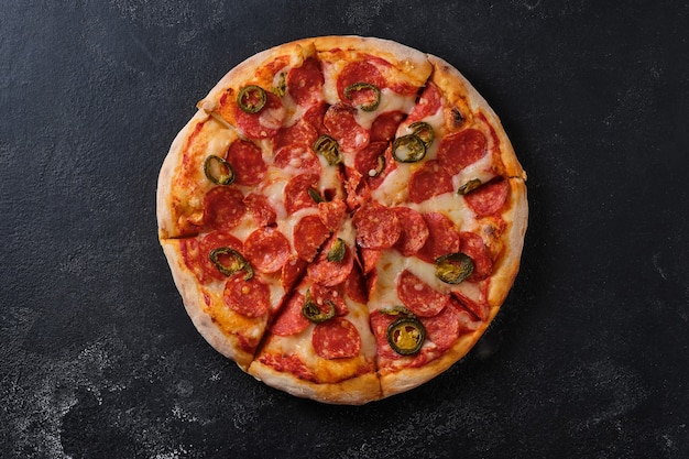 Pizza au pepperoni avec piments jalapenos Un gros plan d'une pizza Mise à plat sur un fond sombre