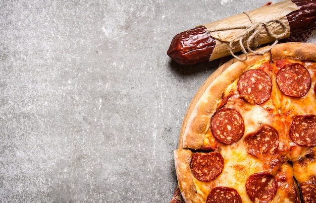 Pizza au pepperoni avec salami et fromage. Sur table en pierre.