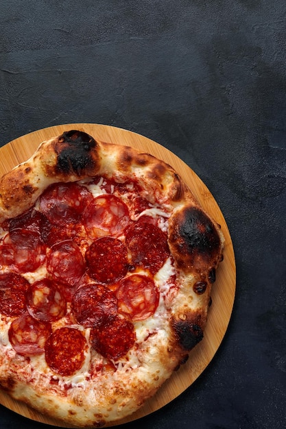 Pizza au pepperoni savoureuse sur fond de béton noir Vue de dessus de la pizza au pepperoni chaud Avec espace de copie pour le texte
