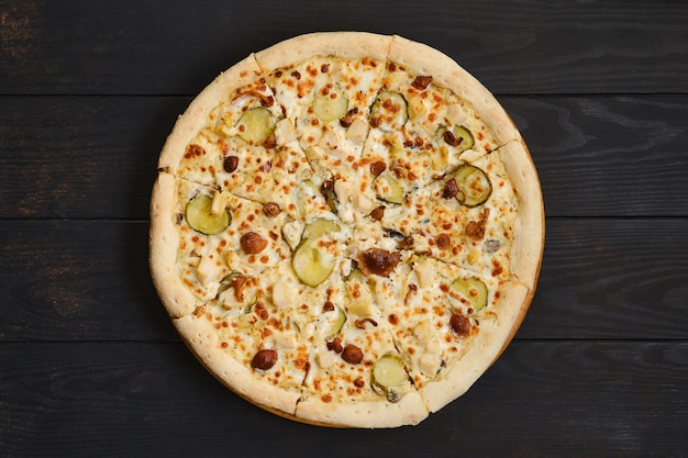 Pizza au poulet, champignons au miel et concombre mariné sur table en bois foncé