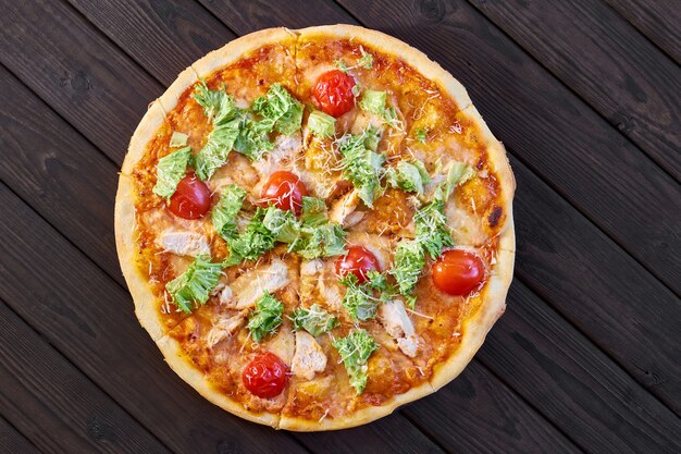 Pizza au poulet, tomates et fromage sur table en bois