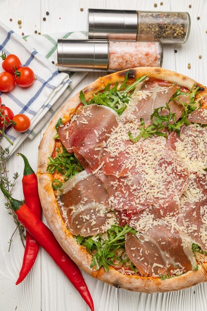 Pizza au prosciutto, roquette, tomates et parmesan