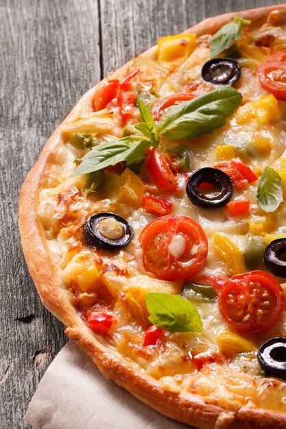 Pizza au salami et légumes sur un vieux fond en bois.