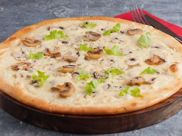 Pizza aux champignons frits et frais sur une planche de bois