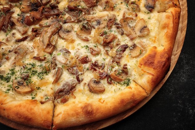 Pizza aux champignons et fromage sur une planche de bois sur fond sombre