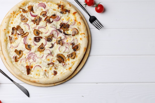 Pizza aux champignons et oignons à bord sur une table en bois blanche se bouchent