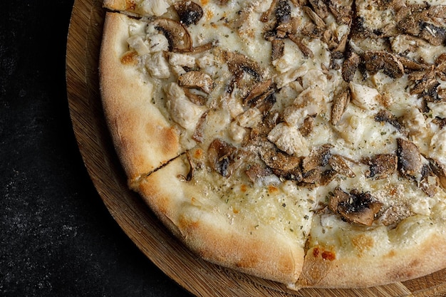 Pizza aux champignons et poulet sur une planche de bois