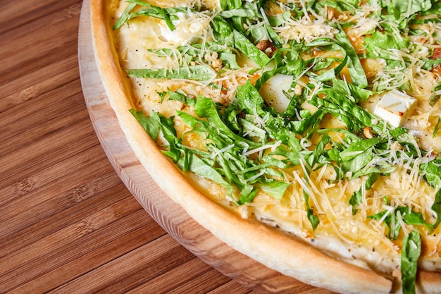 Pizza aux fromages et herbes sur une assiette en bois