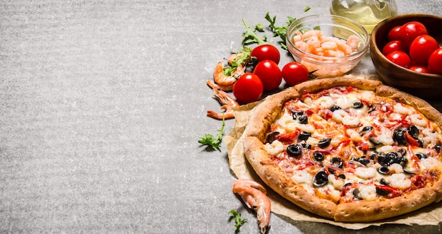 Pizza aux fruits de mer aux crevettes et tomates sur la table en pierre