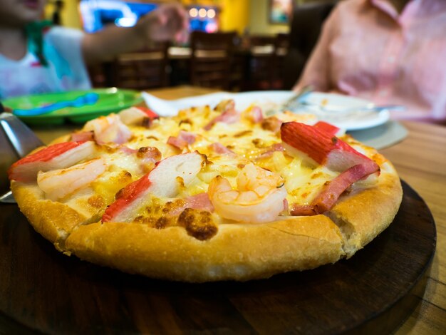 Pizza aux fruits de mer avec crabe, crevettes et jambon Sur un plateau en bois.