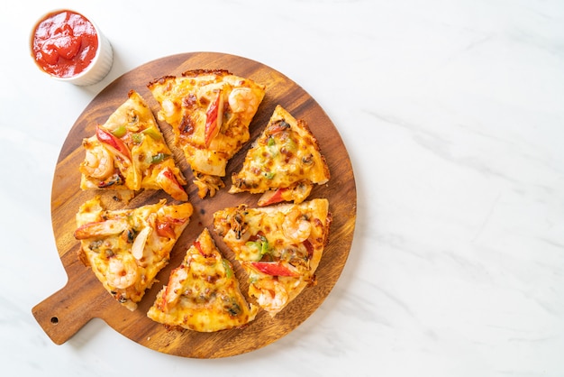 Pizza aux fruits de mer (crevettes, poulpe, moules et crabe) sur plateau en bois