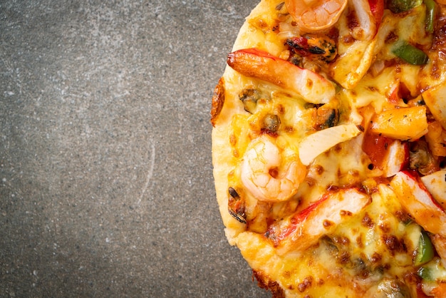 Pizza aux fruits de mer (crevettes, poulpe, moules et crabe) sur plateau en bois