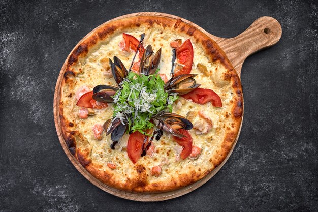 Pizza aux fruits de mer sur planche de bois sur comptoir en pierre sombre