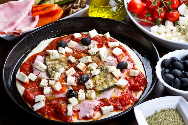 Pizza aux ingrédients de jambon, poivre, courgettes et olives noires