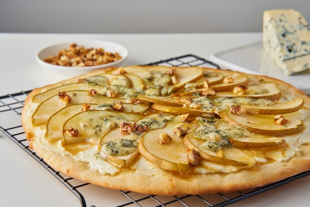 Pizza aux poires sucrées maison aux fruits avec du fromage et du miel, des plats salés italiens rustiques avec de la pâte à pâtisserie, vue latérale