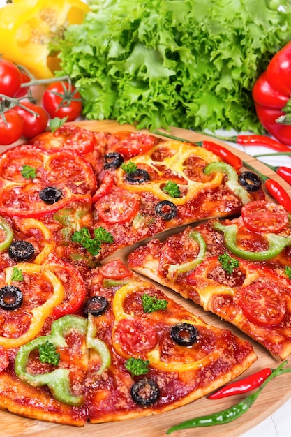 Pizza aux poivrons tomates et olives sur un fond en bois