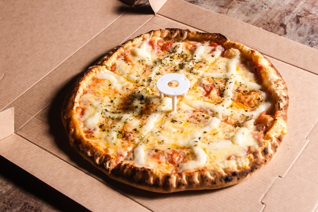 Pizza aux quatre fromages sur une boîte en carton.