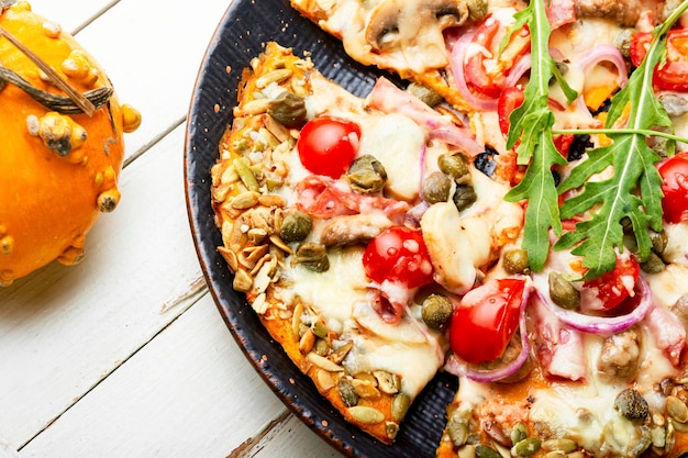 Pizza aux saucisses, tomates et câpres sur une tortilla de citrouille