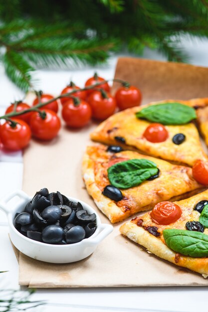 Pizza aux tomates et épinards sur fond blanc et branches de sapin de Noël