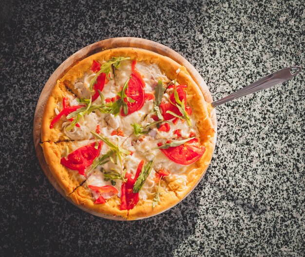 Pizza aux tomates sur une planche de bois.