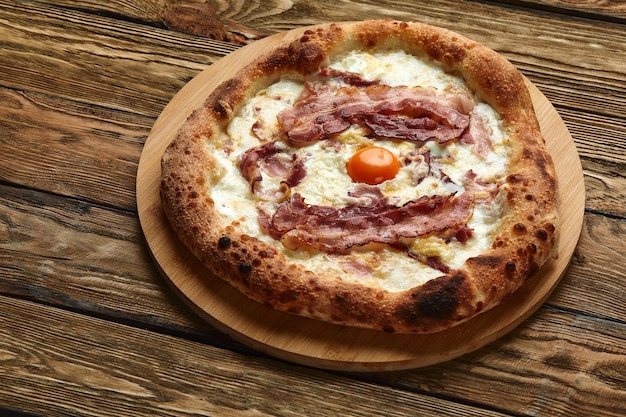 Pizza carbonara avec bacon et oeuf sur fond de bois