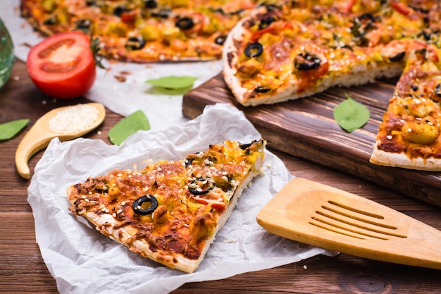 Pizza coupée au poulet, tomates, fromage et olives noires