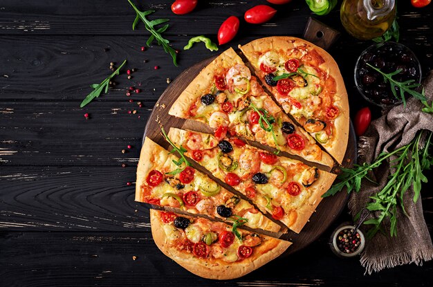 Pizza de crevettes et de moules de fruits de mer délicieux sur une table en bois noire.