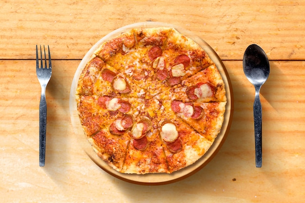 Pizza avec une cuillère et une fourchette sur une table en bois