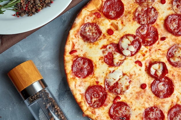 Pizza cuite au four à bois avec fromage fondu et salami chorizo sur fond gris