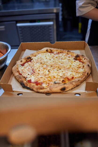 Pizza dans une boîte en carton sur un fond sombre. Espace pour le texte. Livraison de pizzas.