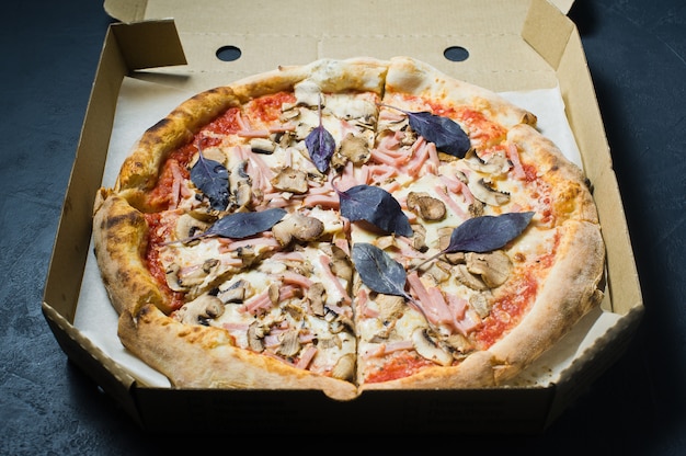 Pizza dans une boîte en carton, fond sombre. Menu de pizza.