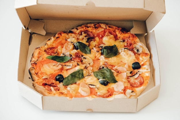 Pizza dans une boîte en carton sur un fond de tableau blanc. Copie, espace vide pour le texte