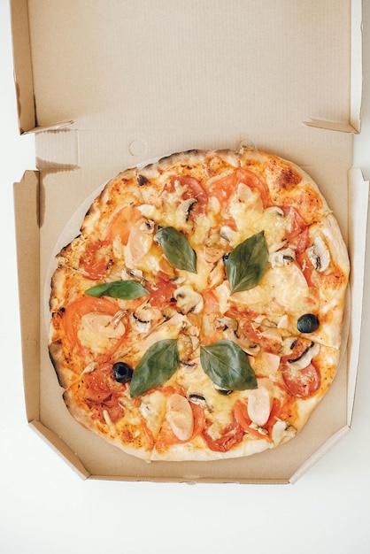 Pizza dans une boîte en carton sur un fond de tableau blanc. Vue de dessus. Copie, espace vide pour le texte