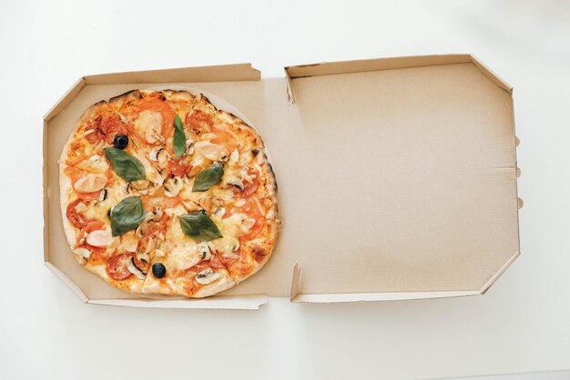 Pizza dans une boîte en carton sur un fond de tableau blanc. Vue de dessus. Copie, espace vide pour le texte