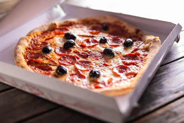 Pizza dans une boîte en carton sur table prête pour le client