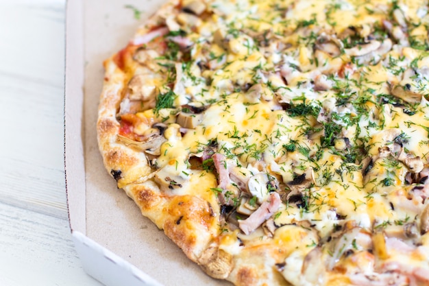 Pizza dans une boîte. Pizza sur un fond en bois blanc