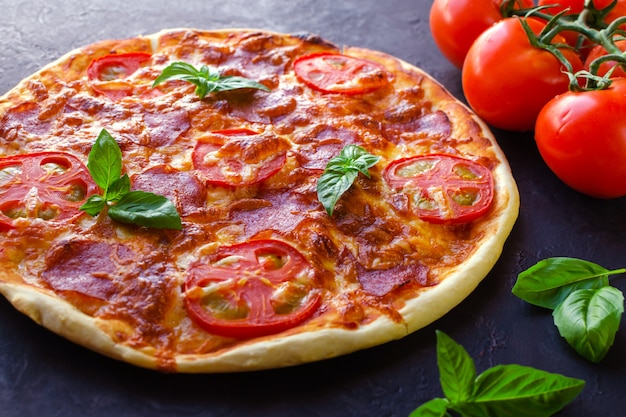 Pizza épicée maison avec saucisse et tomate.