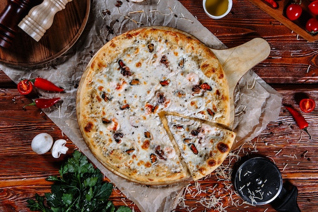 La pizza est sur la table de la cuisine et les ingrédients sont éparpillés