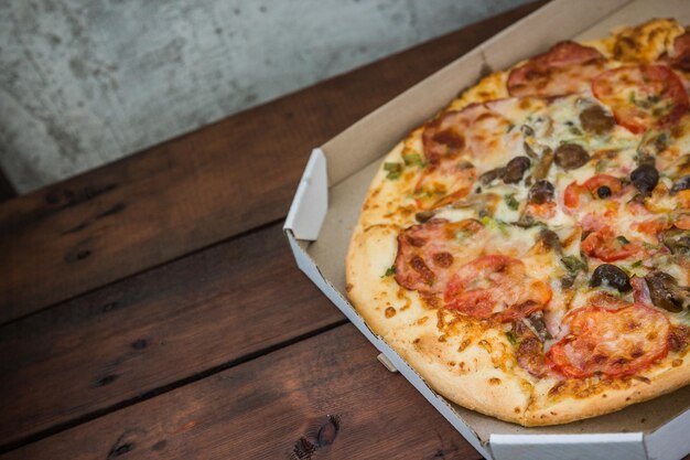 Pizza sur fond de bois dans un style rustique pizza italienne dans une boîte en carton espace de copie