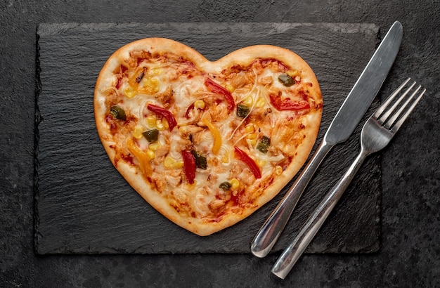 Pizza en forme de coeur pour la Saint Valentin sur ardoise avec couverts